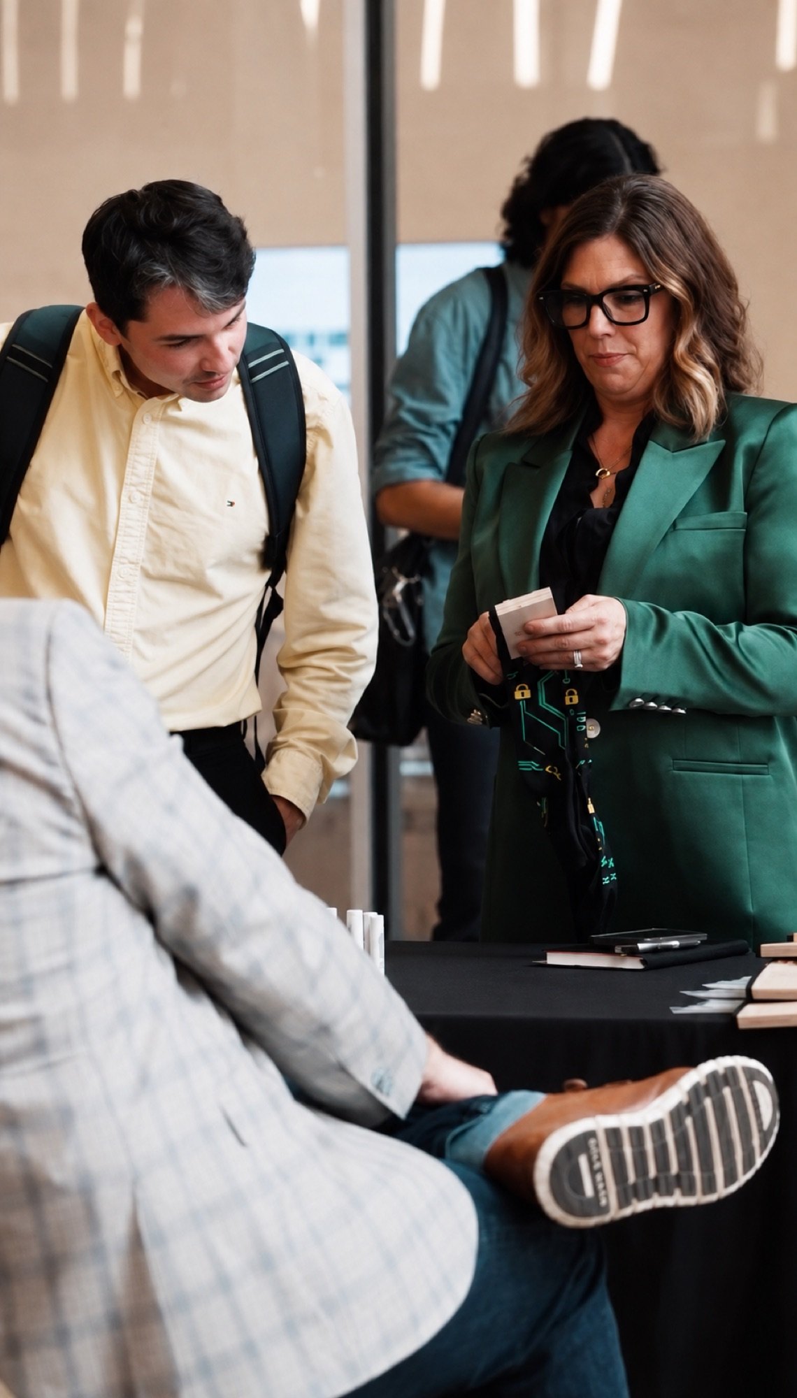Attendees in a business conversation around a table, one checking her phone
