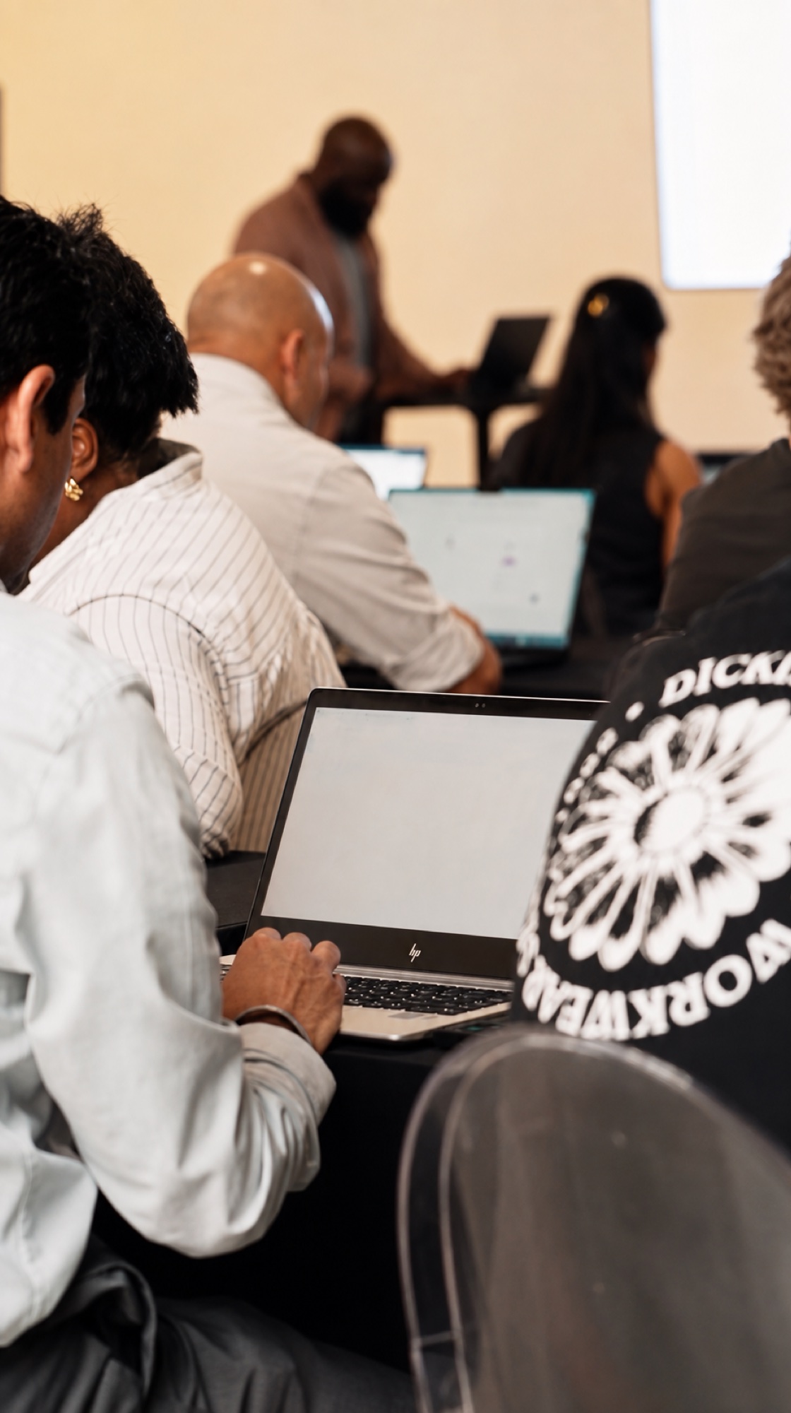 Attendees working on laptops around a table during a hands-on workshop