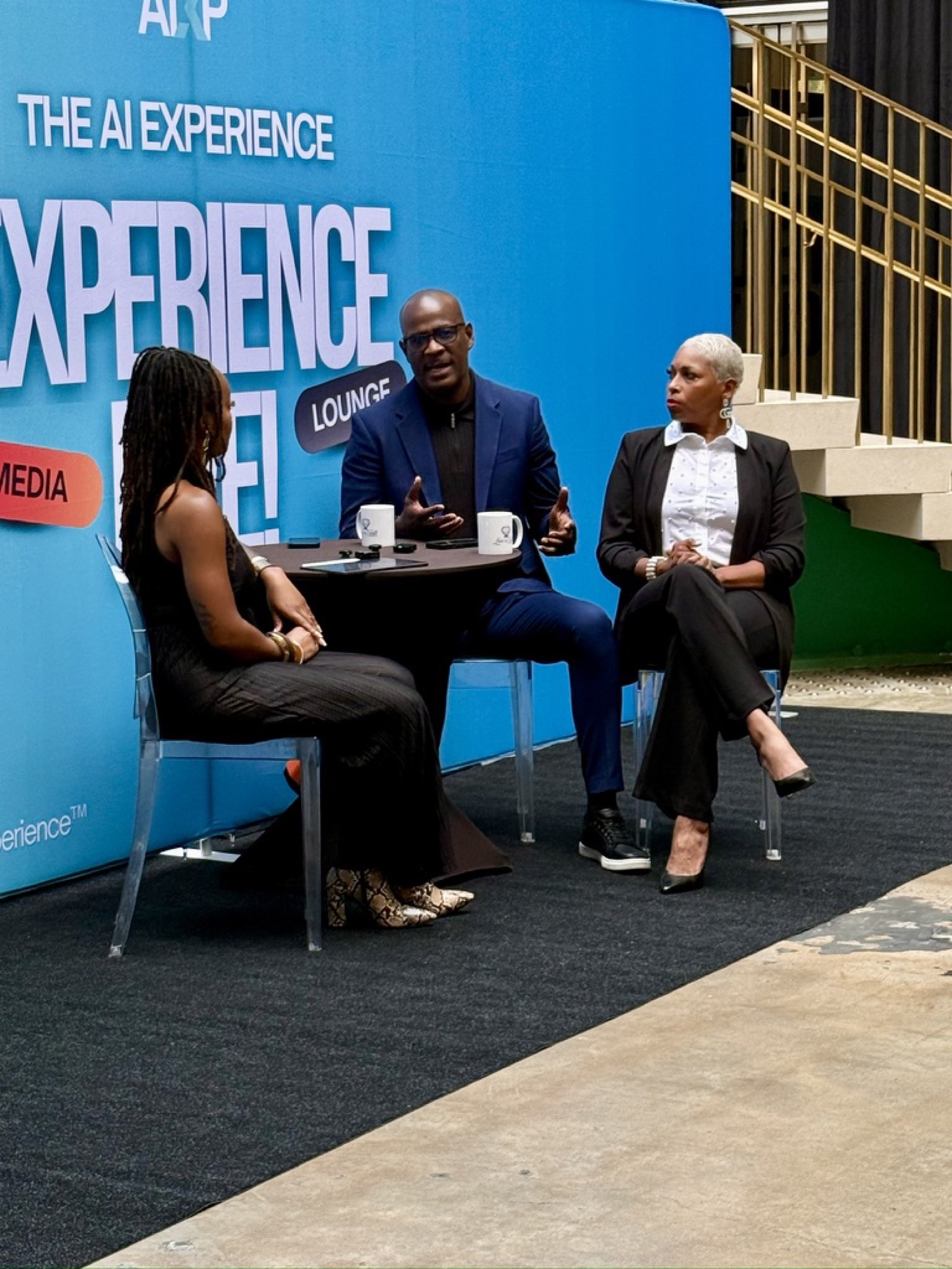 Three guests in conversation around a small table in the Experience Live! media lounge